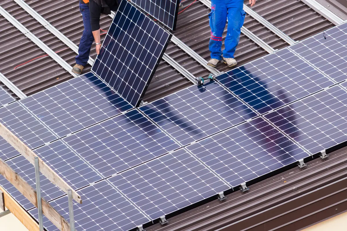 Operarios instalando placas solares sobre una cubierta de Úbeda para calcular su precio