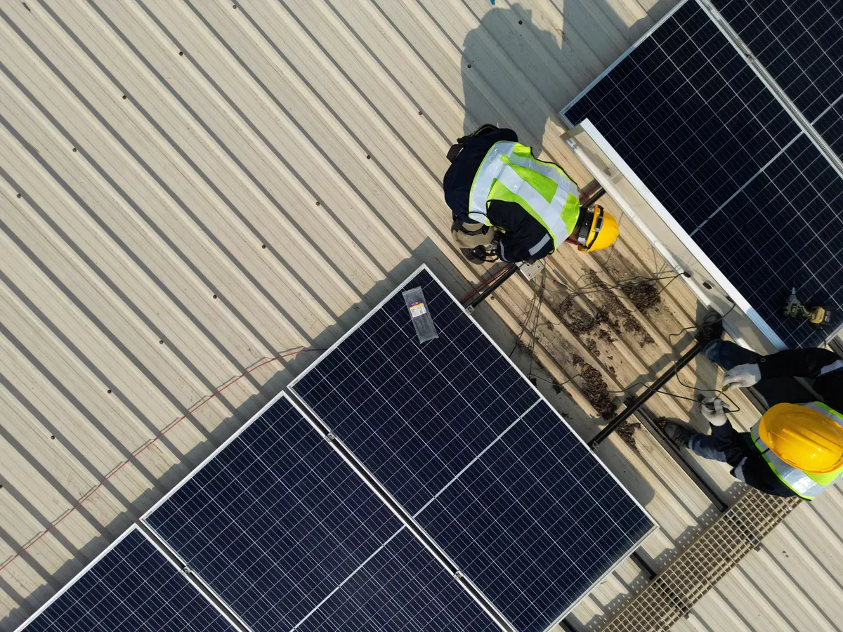 Vista aérea de operarios instalando placas solares sobre la cubierta de una nave industrial en Úbeda